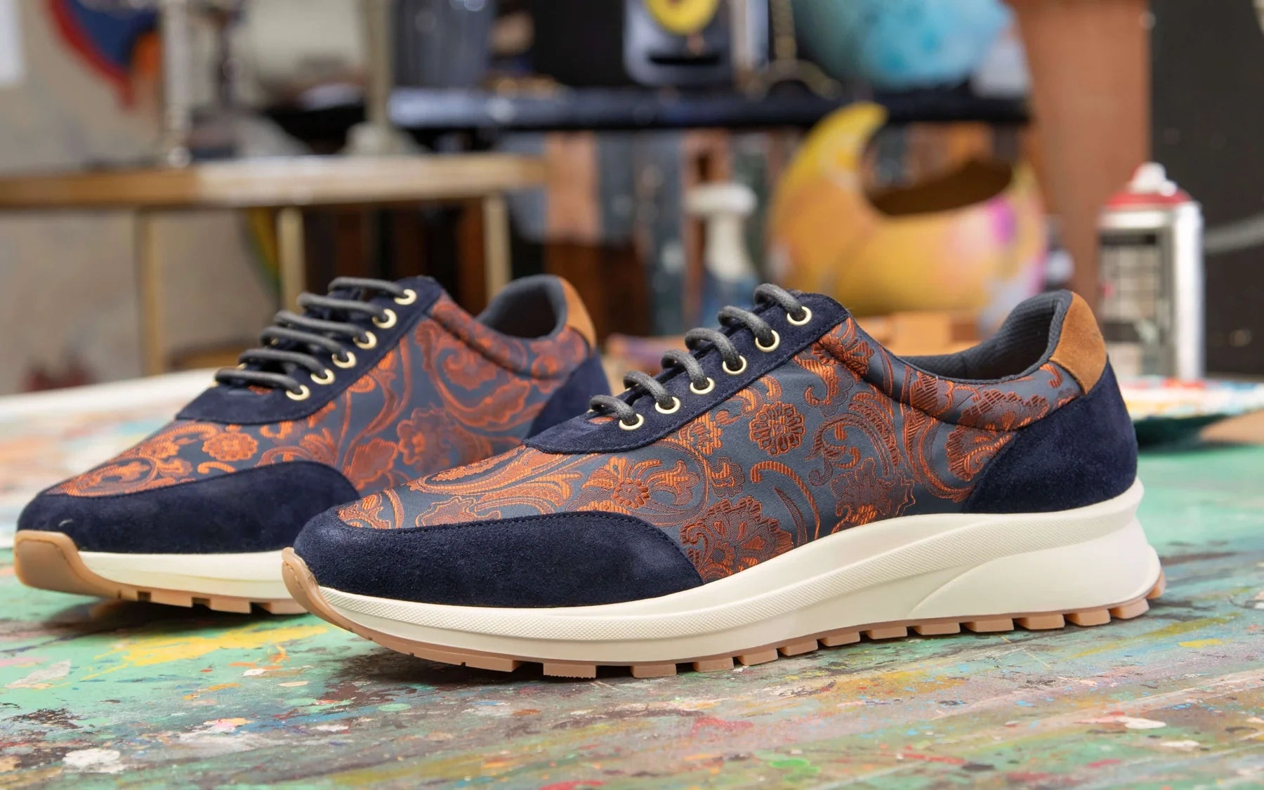 Hora Azul sneakers op een met verf bedekte tafel in het kunstenaarsatelier
