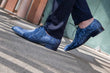 Blue Sassaniden gedragen onder een donkerblauwe krijtstreeppantalon, in een artistiek gekantelde compositie — originele gedragen schoenfoto
